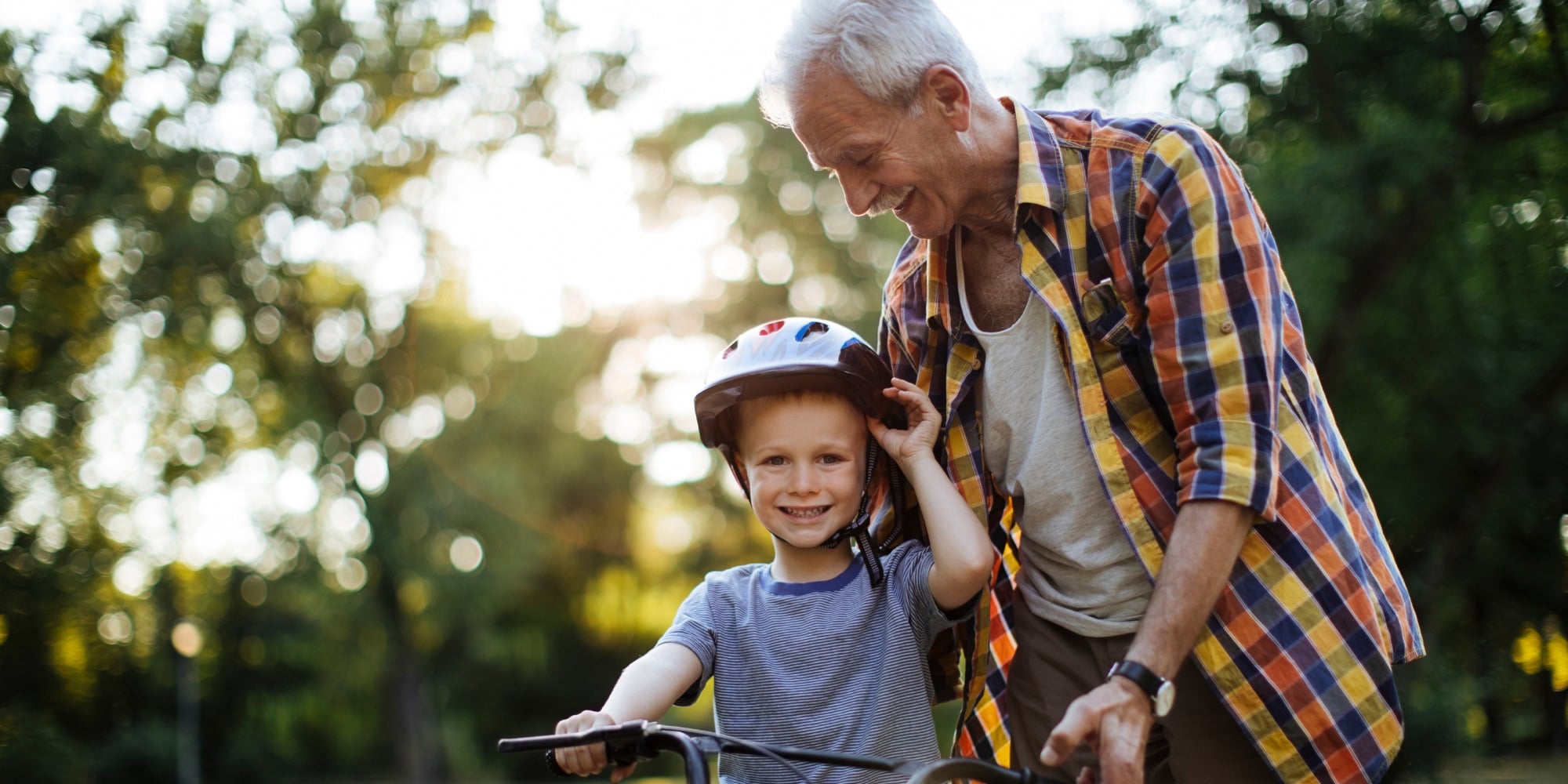 A grandfather helping his grandson with a bike helmet