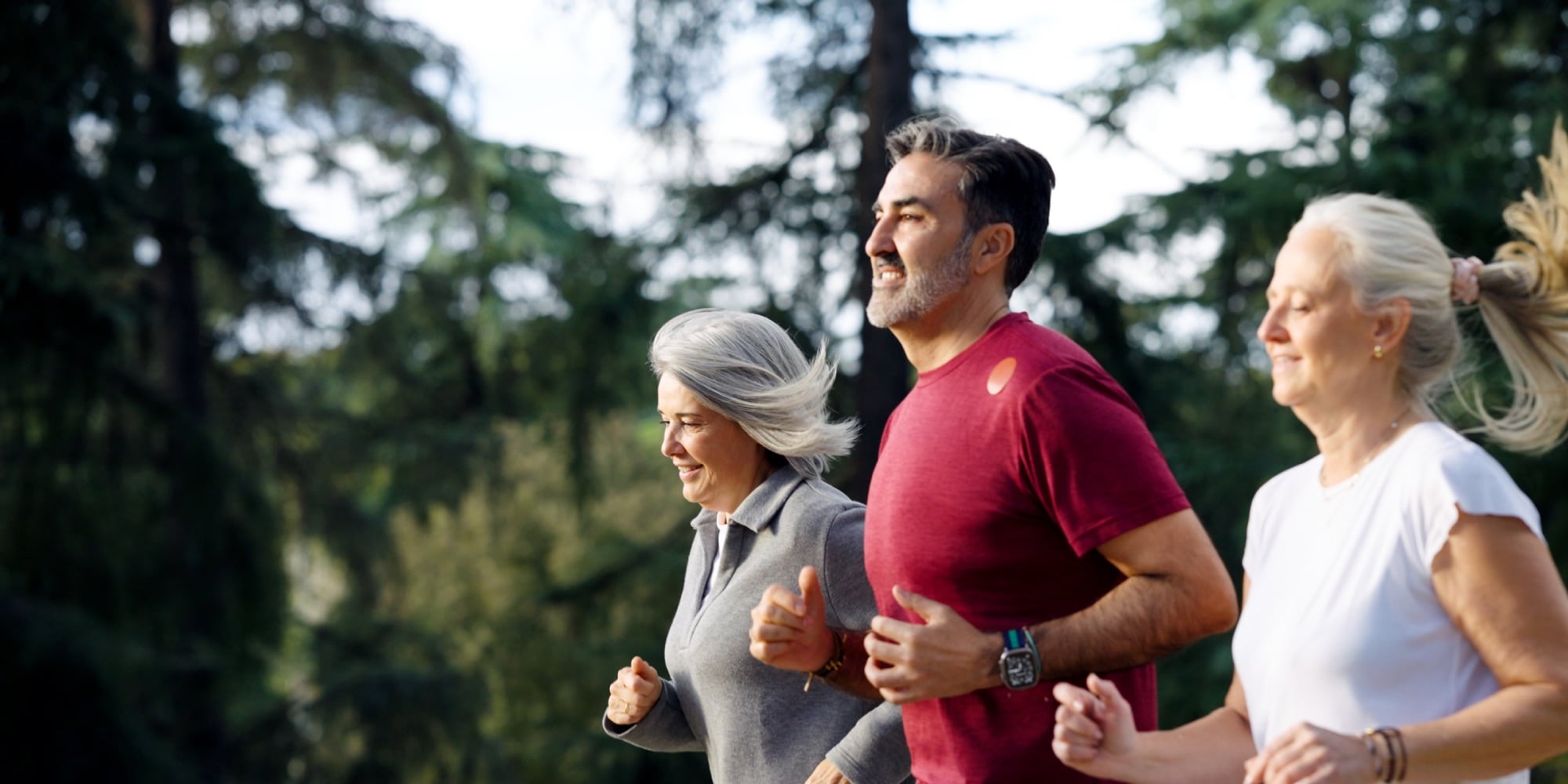 Three adults running together outdoors